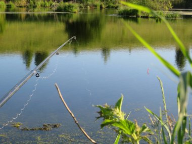 Bir makara ve akşam dönen yaz gölü, gölde balık tutan