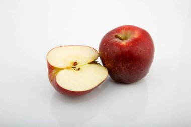 Beyaz arka planda bir elma ve yanında yarım elma ile kompozisyon.
