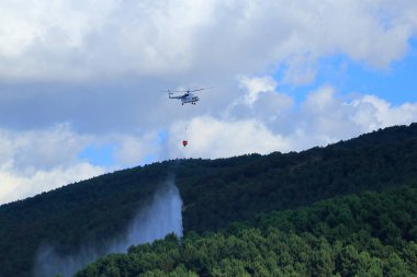 Yangın söndürme helikopteri orman kaplı dağda başlayan yangına müdahale ediyor..