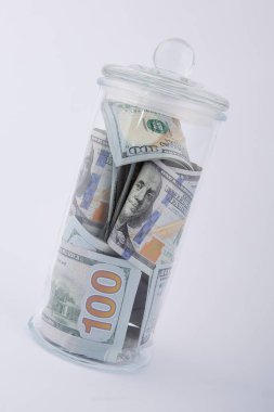 Beyaz bir arka planda, Amerikan dolarlarının kompozisyonu cam kavanozda.