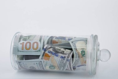 Beyaz bir arka planda, Amerikan dolarlarının kompozisyonu cam kavanozda.