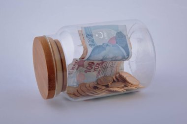 Altın sikkelerin ve banknotların beyaz arka planda kavanozdaki görüntüsü