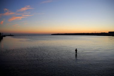 Gün batımında balıkçı. Sakin bir akşamda kıyıya yakın sığ sularda balık tutan bir adam. Silivri, Türkiye