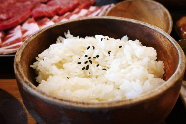 Susamlı pirinç dolu tahta bir kase. Biraz çiğ et..