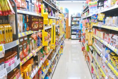 Arkaplan olarak renkli rafları olan bulanık süpermarket koridoru.