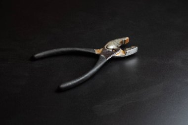 Koyu arkaplanda kopyalama alanı olan pense ve siyah renkli kauçuk saplar.