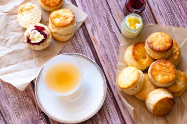 Manzara beyaz bir fincan çay ve geleneksel İngiliz çörekleri ahşap masada, kahvaltılık yemek zamanı. .