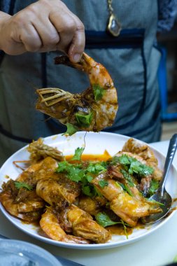 Şefin eli, restoranda tabakta lezzetli pişmiş dev karides karidesini, Tayland yemeğini tutarken yakın çekim..