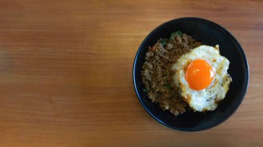 Üst düzey yemek kızarmış domuz ve biberli fesleğen, ahşap masada kızarmış yumurta, Tayland yemeği. Metin için alanı kopyala
