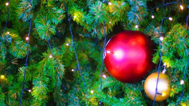 Süslü bir Noel ağacına asılı kırmızı takı, ışık ve Noel temalı..