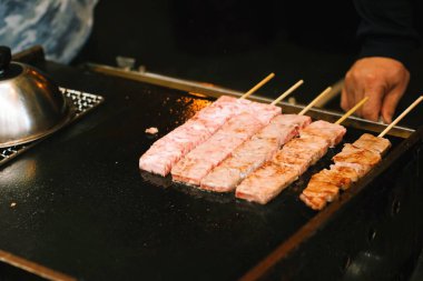 Siyah kızgın demir tavada ızgara yapan et şişleri. Sokak yemekleri konsepti.