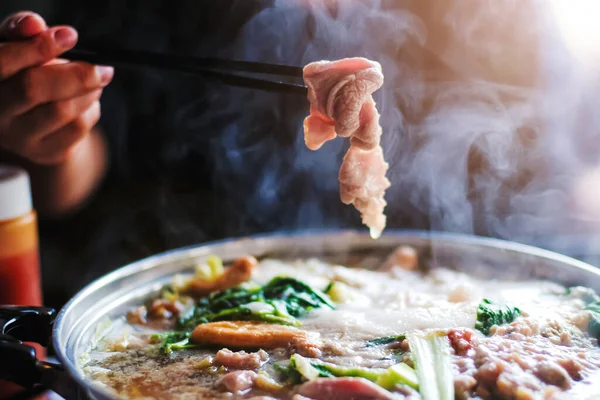 Shabu shabu tarafından dilimlenmiş sığır eti tutan kadın Kore usulü veya ince dilimlenmiş et ve sebzelerin olduğu sıcak tencerede Japon usulü sığır etidir. Tayland 'ın en popüler yemekleri..