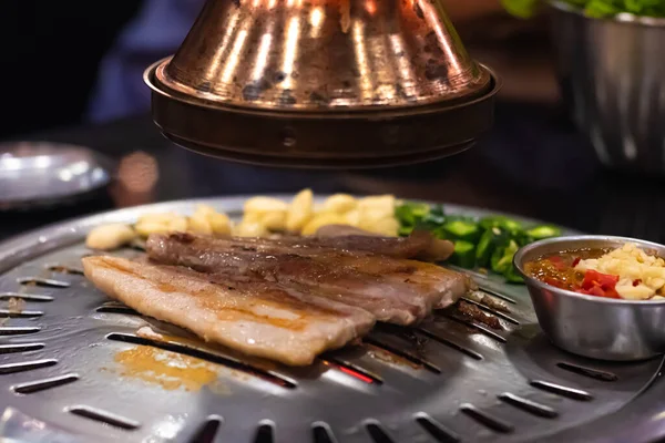 Sıcak tavada leziz taze domuz eti ızgarası ve Kore restoranında Kore usulü barbekü sosu tüttüren kırmızı biberli sarımsak. Geleneksel popüler Kore yemekleri.