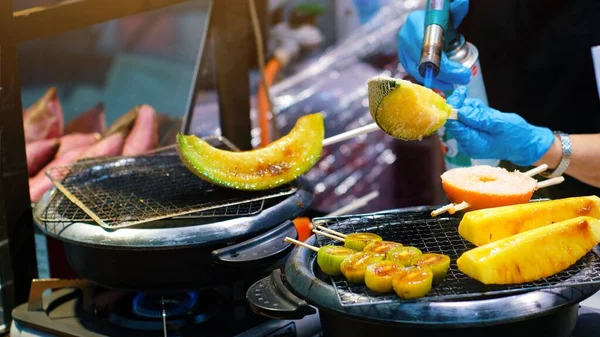 Kuromon pazarında satmak için fırında Japon kavunları ve diğer meyveleri dilimlenmiş brülör yanığı kullanan bir şef. Cantaloupes BBQ, Osaka Japonya 'ya gelen turistler arasında popülerdir..