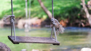 Eski halat boş ahşap salıncak nehir kenarında doğa parkı yakınında, yaz tatili.