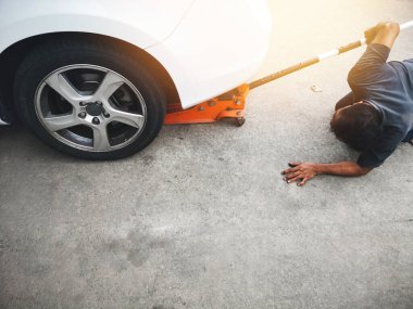 Araba lastiği değiştirmek için acil durum krikosuyla araba soyan bir tamirci. araba tamiri.