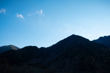 Doğanın, siluet dağ sıraları tepeleri ve sonbaharda Kamikochi Ulusal Parkı 'nda açık mavi gökyüzü arkaplanı ile manzarası Japonya