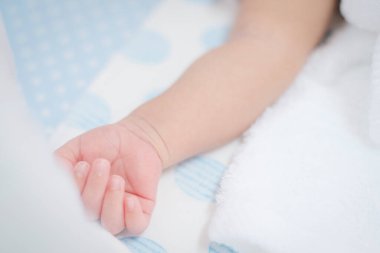 Sevimli küçük kol parmakları bebeğin derisini yatağın üzerinde tutuyor..