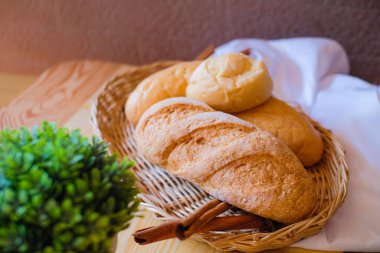 Tahta masada, üzerinde beyaz bez ve yeşil saksı olan taze pişmiş lezzetli ekmek..