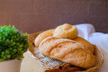Tahta masada, üzerinde beyaz bez ve yeşil saksı olan taze pişmiş lezzetli ekmek..
