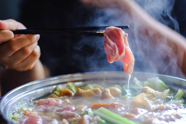 Shabu shabu tarafından dilimlenmiş sığır eti tutan kadın Kore usulü veya ince dilimlenmiş et ve sebzelerin olduğu sıcak tencerede Japon usulü sığır etidir. Tayland 'ın en popüler yemekleri..