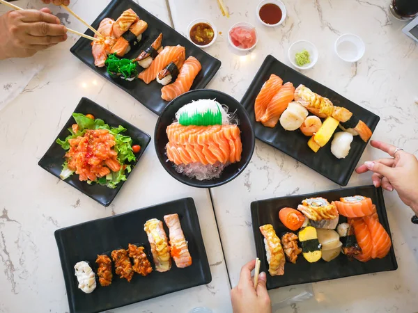 日本の伝統料理のトップビューレストランのテーブルの上に並べられた寿司ロール 竹棒を使って寿司ロールを食べる人の手 — ストック写真