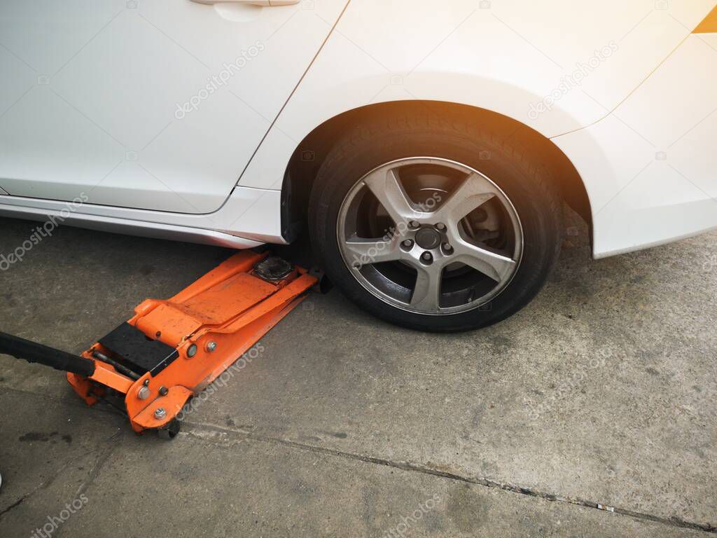jacking up a car with the emergency jack for changing car tire. car fixing.