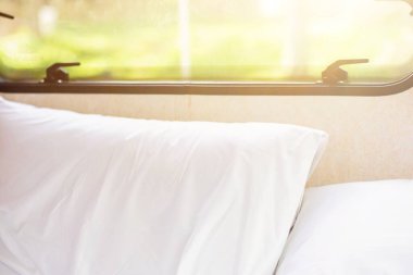 Boş beyaz yastıklar, rahat yatağın üzerinde, pencerenin yanında, sabah güneş ışığı altında. dinlenme, iç mekan, konfor ve yatak konsepti.