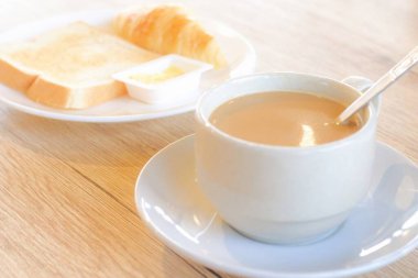 Taze lezzetli kahvaltı, beyaz bardakta sıcak kahve ve ahşap masada kızarmış ekmek..