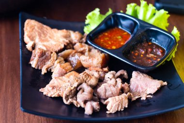 Pişmiş haşlanmış domuz eti, siyah tabakta et, tatlı ve baharatlı biber sosuyla yenir. Tayland tarzı yemek..