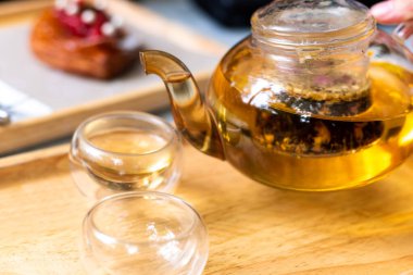 Çay yapraklı sıcak su çaydanlıktan bir fincana dökülür. Çay demleme süreci, çay töreni, bir fincan taze demlenmiş çay, çay molası..