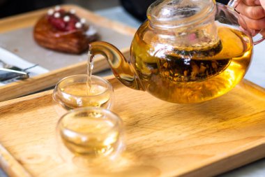 Çay yapraklı sıcak su çaydanlıktan bir fincana dökülür. Çay demleme süreci, çay töreni, bir fincan taze demlenmiş çay, çay molası..