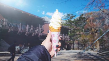 Bir kadının el ele tutuşması Yumuşak beyaz sütlü dondurma külahı açık mavi gökyüzü arka planında