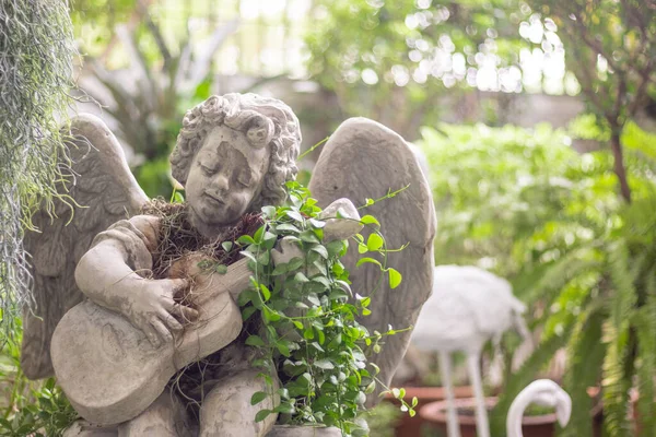 Cute cupid statue playing guitar music decorated in garden