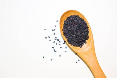 Tahta kaşıkta siyah susam tohumları beyaz arka planda izole edilmiş.