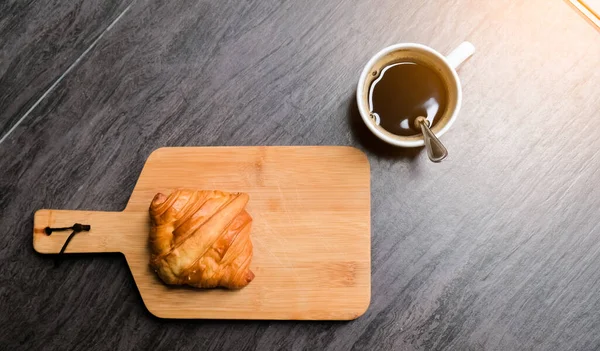 早上在木板上放上新鲜美味的羊角面包和黑咖啡 早上有阳光 喝咖啡休息 放松身心 — 图库照片