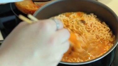 Aşçının eli, mutfakta yumurta ve etle lezzetli Tayland usulü hazır şehriye pişiriyor.