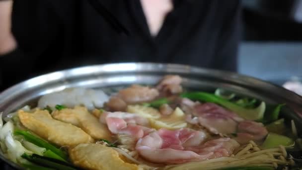 用筷子炒牛肉肉片的妇女是韩国或日本风格的牛肉 放在热锅里 热锅里有薄片肉和煮在水里的蔬菜 美味佳肴在泰国最受欢迎 — 图库视频影像