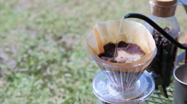 Kavrulmuş kahvenin üzerine su dökmek çaydanlıktan kahve filtresine. Ormandaki bir yaz kampında taze sabah kahvesi demliyorum.