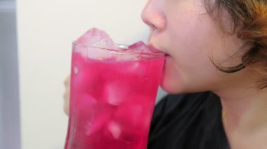 Genç Asyalı kadın kırmızı soda içiyor yoğunlaştırılmış aromalı şerbet içinde buzlu şerbet, yazın tatlı ve ferahlatıcı içecek.