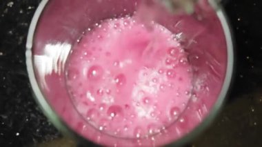 Kırmızı yoğunlaştırılmış şerbetli bir bardağa soda dökülüyor, içeceğe hazırlanıyor.
