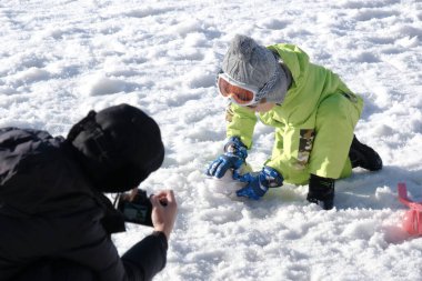 Donmuş kar zemininde kar topu oynayan, güneşli bir kış tatilinde kış oyunları oynayan sevimli çocuklar..