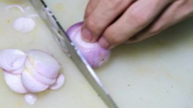 Yakın plan şef bıçağı sürgüsü kesme tahtasındaki soğanları kesiyor.