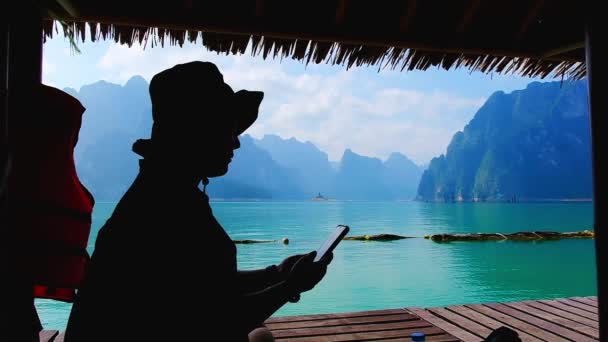 在泰国霍索克国家公园的竹筏上 年轻的观光旅游妇女用智能手机在石灰岩山背景的竹筏上悠闲自在地享受暑假 — 图库视频影像