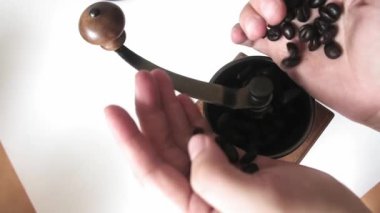 Kavrulmuş kahve çekirdeklerinin el yapımı kahve öğütücüsüne el ele tutuşup düşmeleri.