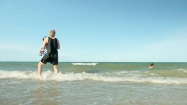 Mutlu aile babası ve oğlu, yazın Tayland 'da tropikal sahilde dalgalarla birlikte açık havada eğleniyor.