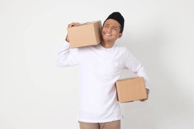 Koko gömlekli çekici Asyalı Müslüman adamın portresi. Karton kutu taşırken minnet dolu ve huzurlu hissediyor. Bayram için eve gidiyorum. Beyaz arkaplanda izole edilmiş resim