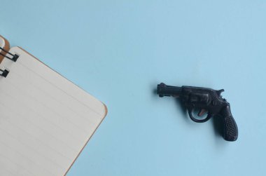 mavi arkaplanda oyuncak silah ve defter, boş alan