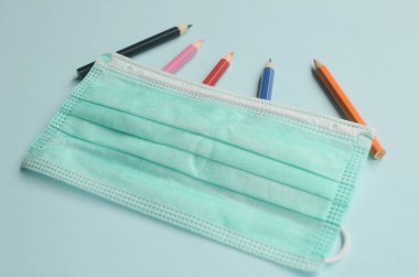 Mavi arkaplanda renkli kalem ve maskelerle üst görünüm boşluğu