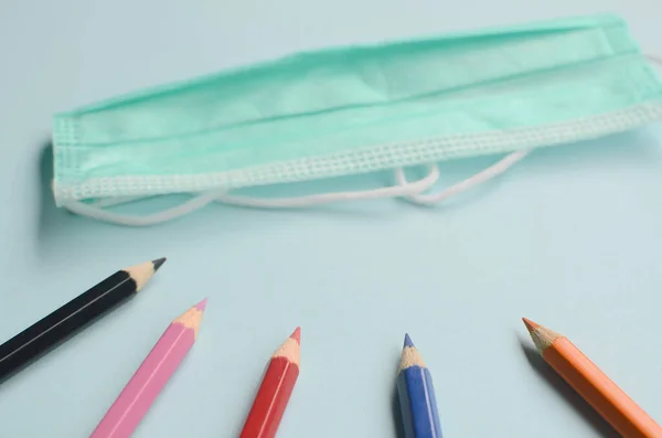 Mavi arkaplanda renkli kalem ve maskelerle üst görünüm boşluğu